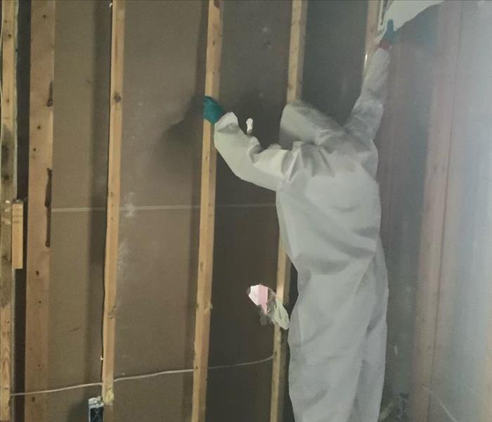 man in hazmat suit rips wall down during restoration 
