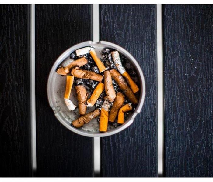 An ashtray with old smoked cigarettes stands on a black table top view, day