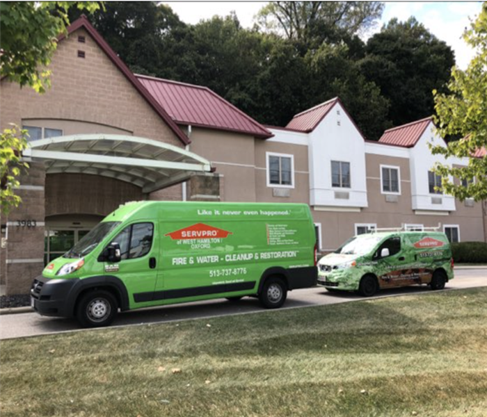 Two green SERVPRO trucks parked outside of property.
